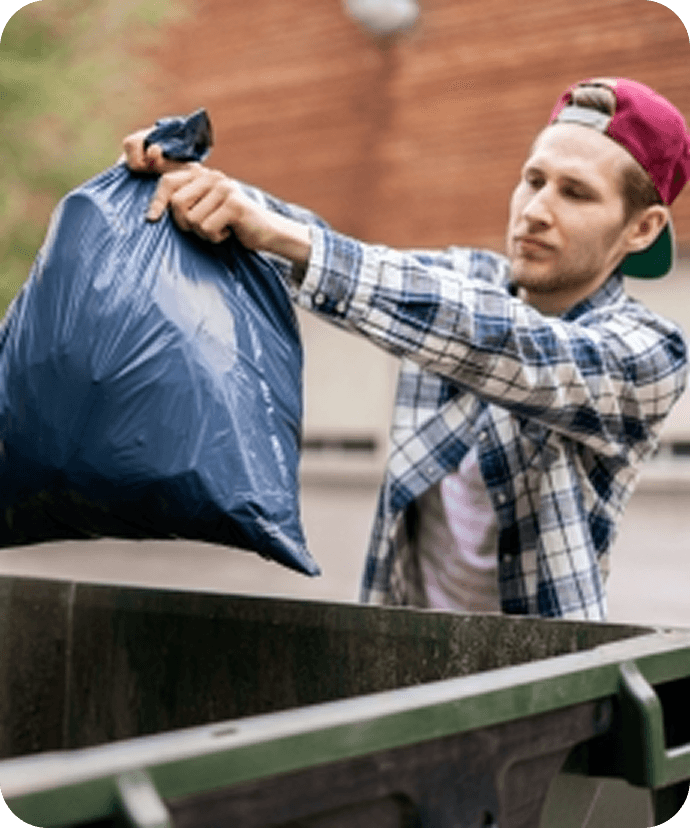Worker throwing a trash bag into a bin
